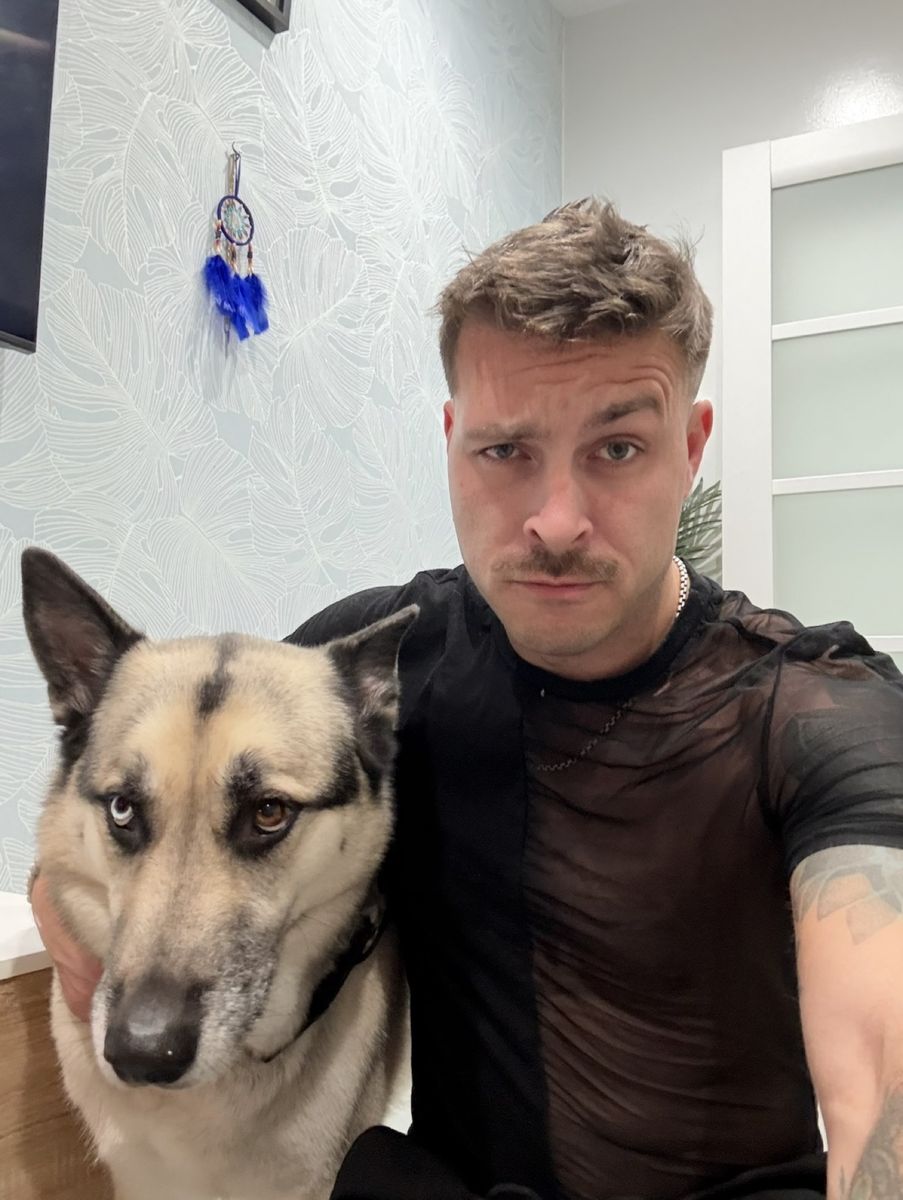 Nick, in a black mesh tee, taking a selfie with his German Shepherd/husky mix Finn sitting right in front of him